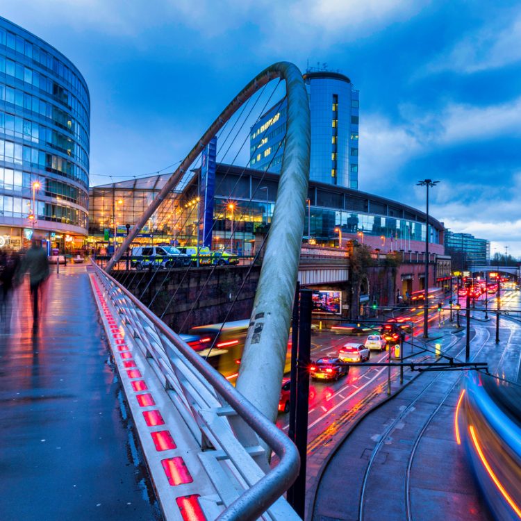 A long exposure of Manchester Piccadilly showing silhouettes of people moving and strikes of lights from the trams passing.